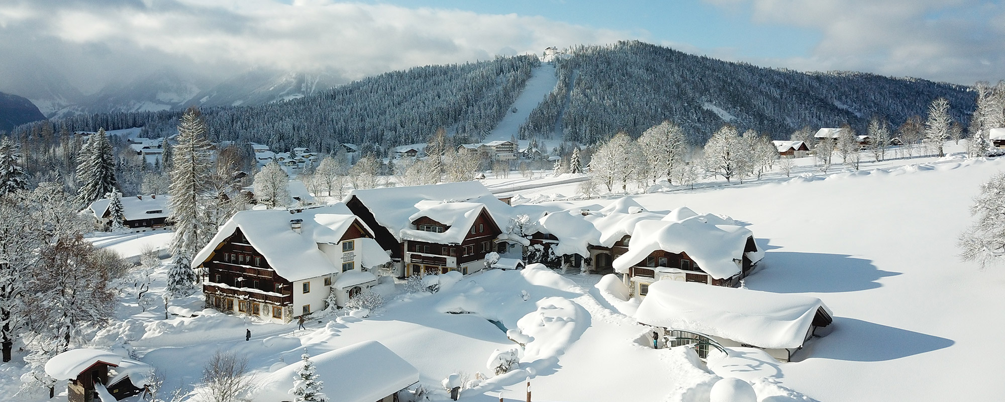Luftaufnahme über der winterlichen Landschaft rund um den Bio-Bauernhof Simonbauer mit Apartments, Ferienhaus, Penthaus und Zimmer in Ramsau am Dachstein