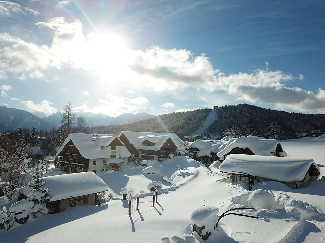 Luftaufnahme über der winterlichen Landschaft vom Urlaubsdorf Bio-Bauernhof Simonbauer mit Apartments, Ferienhaus, Penthaus und Zimmer in Ramsau am Dachstein